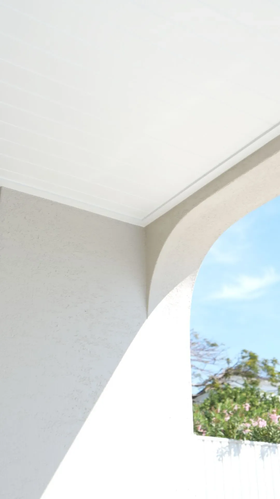 Freshly painted white archway and eaves against a clear blue sky