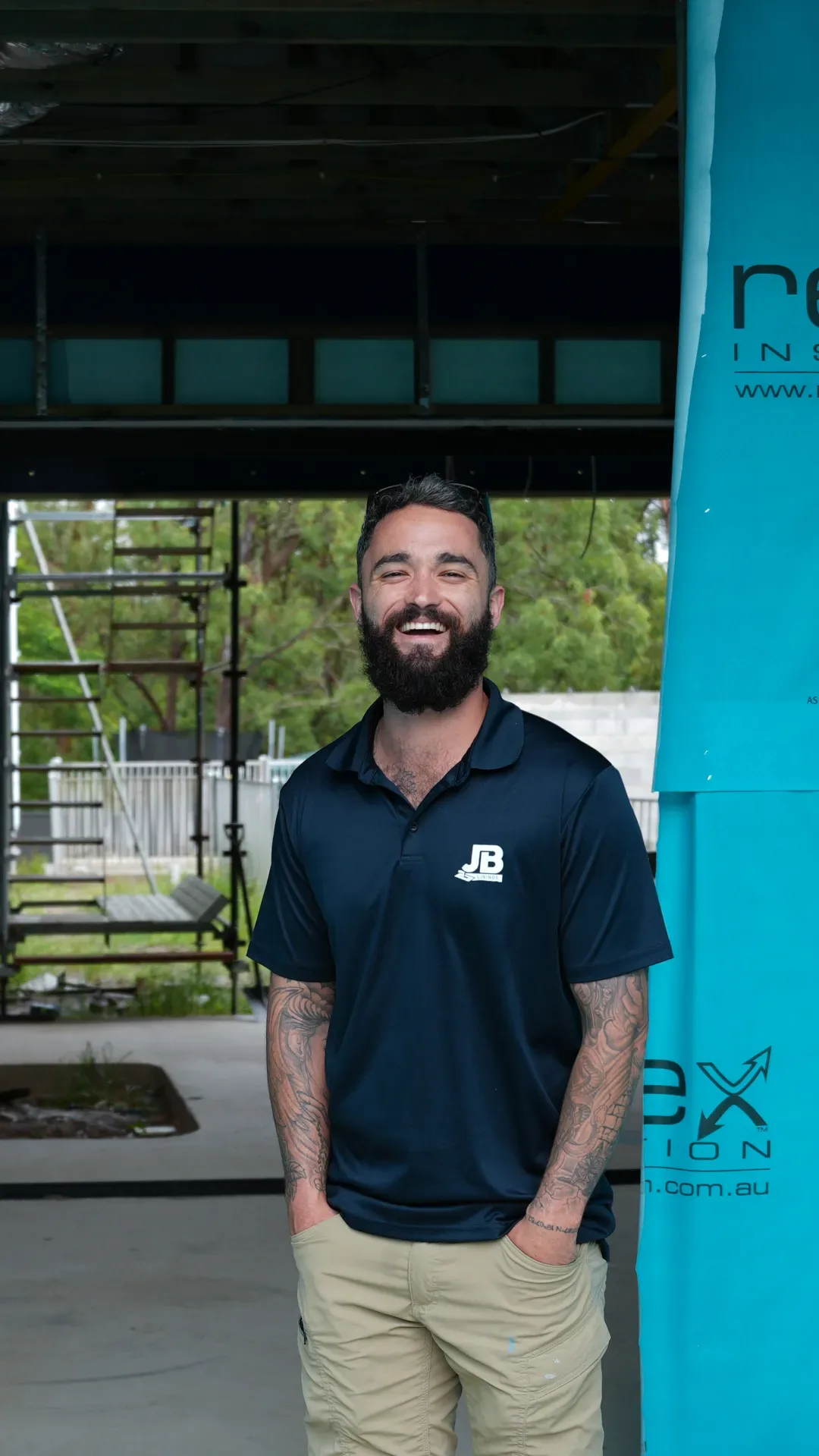 Tradesman in a JB Linings polo smiling on a residential construction site